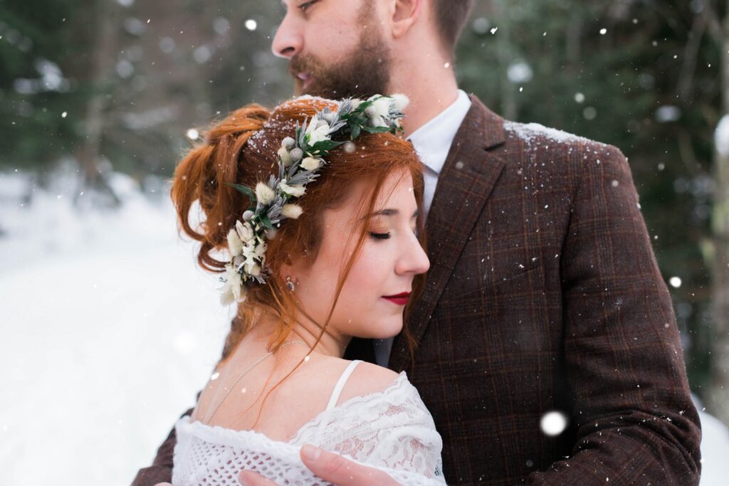 Couple qui s'enlace pour prendre une photo de couple sous la neige